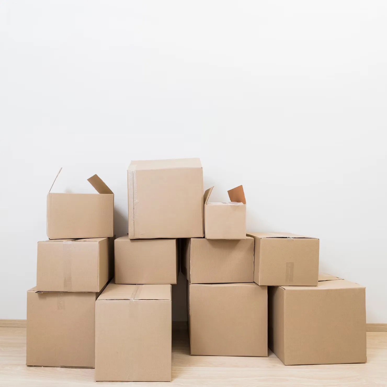 stacked-moving-cardboard-boxes-against-white-wall_23-2148060001
